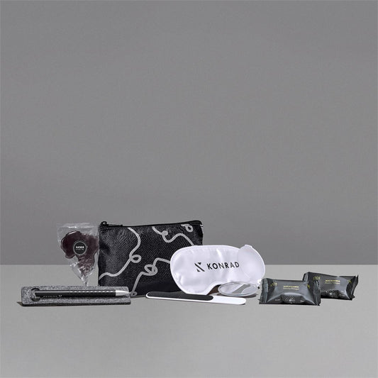 Travel kit with pouch, eye mask, and other items on a gray background

