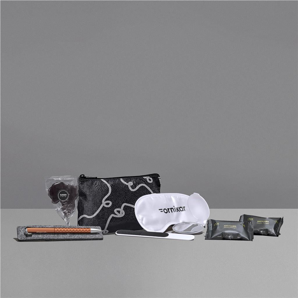 Collection of travel-sized products including a pouch, eye mask, and other items on a gray background

