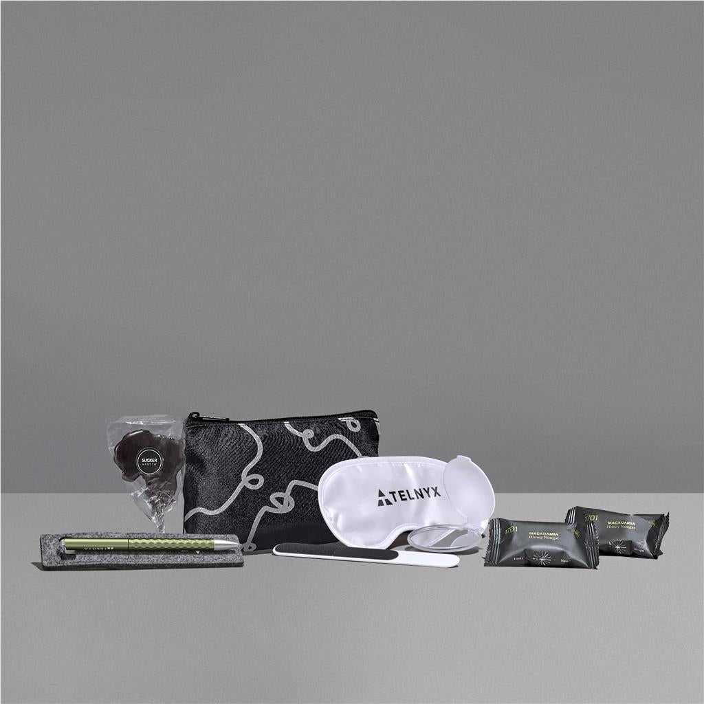 Travel kit with pouch, eye mask, and other items on a gray background

