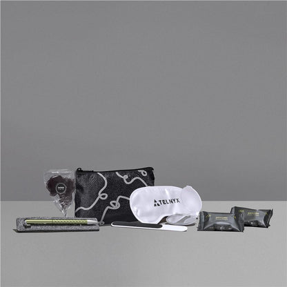 Travel kit with pouch, eye mask, and other items on a gray background

