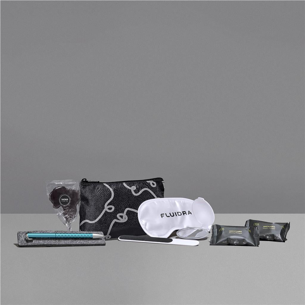 Collection of travel items including a pouch, eye mask, and other small packets on a gray background

