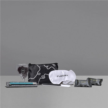 Collection of travel items including a pouch, eye mask, and other small packets on a gray background


