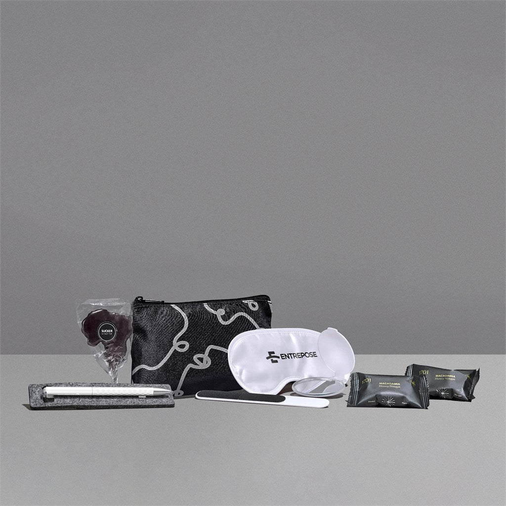 Collection of travel items including a pouch, eye mask, and packets on a gray background


