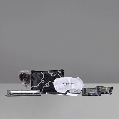 Collection of travel items including a pouch, eye mask, and packets on a gray background

