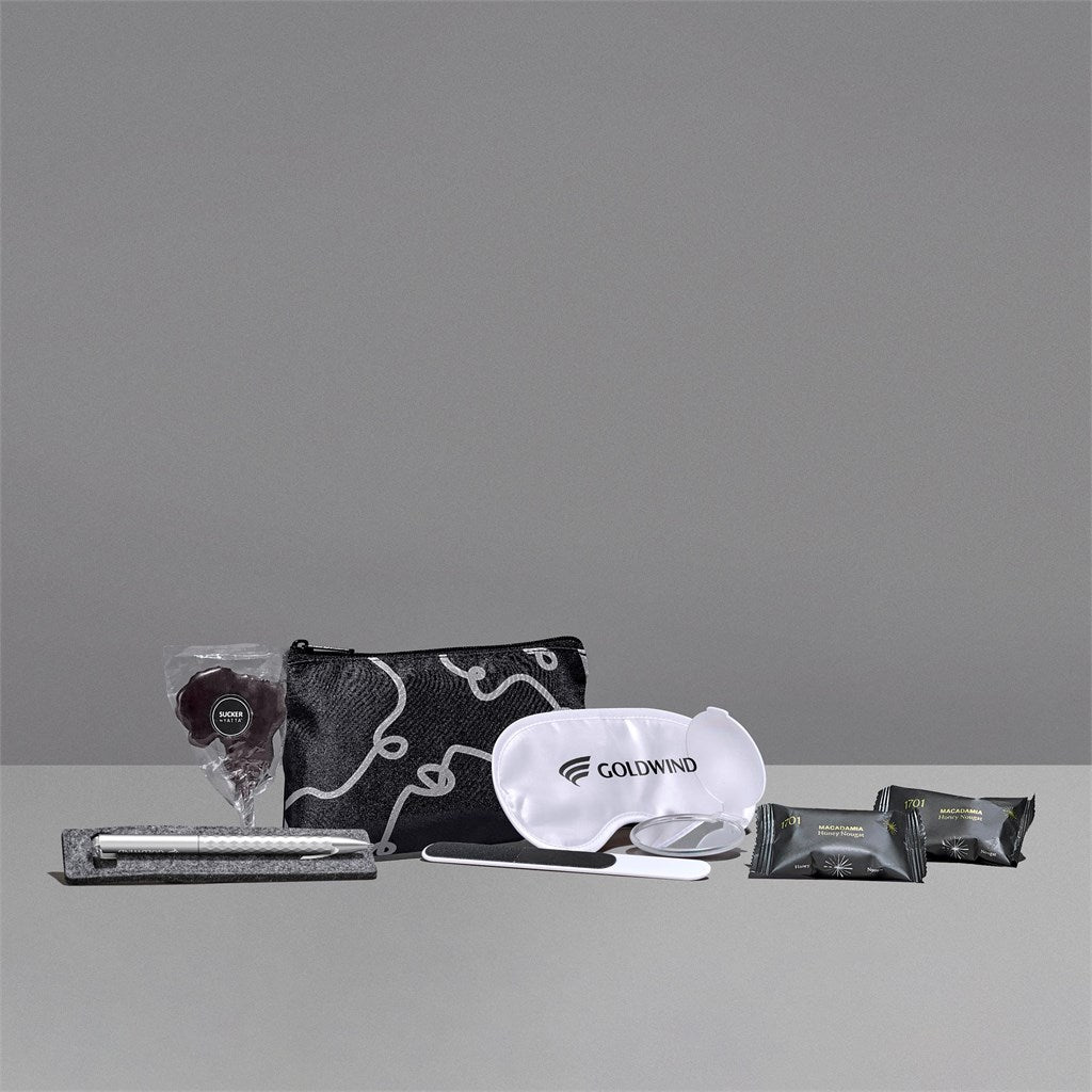 Collection of travel items including a pouch, eye mask, and packets on a gray background

