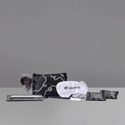 Collection of travel items including a pouch, eye mask, and packets on a gray background

