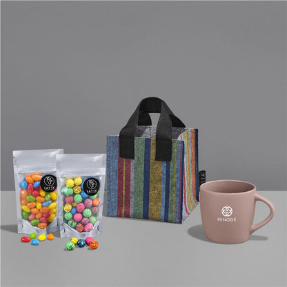 Colorful candies in bags, a striped gift bag, and a pink mug on a gray background

